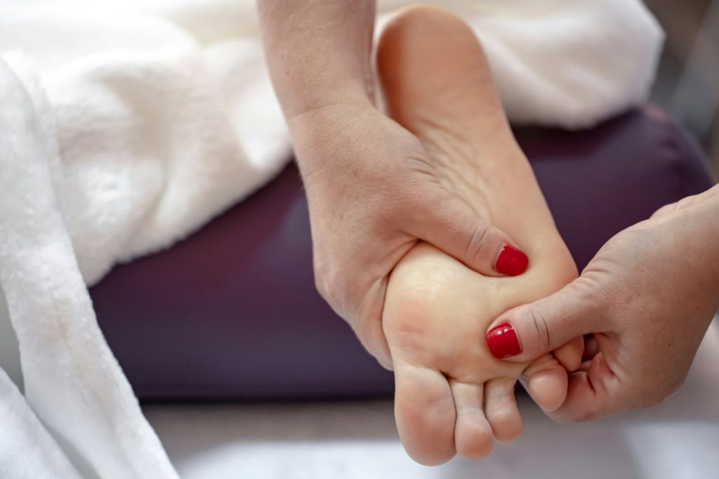 Close-up of hands of masseur doing massage of female feet.